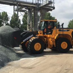 Gele Hyundai wiellader schept steenslag op bij een asfaltcentrale voor de productie van asfalt.